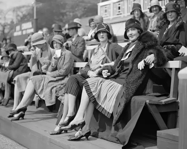 Frauen in eleganten Hüten und Kleidern, ein Bild der Weimarer Republik Mode, sitzen auf einer Tribüne.