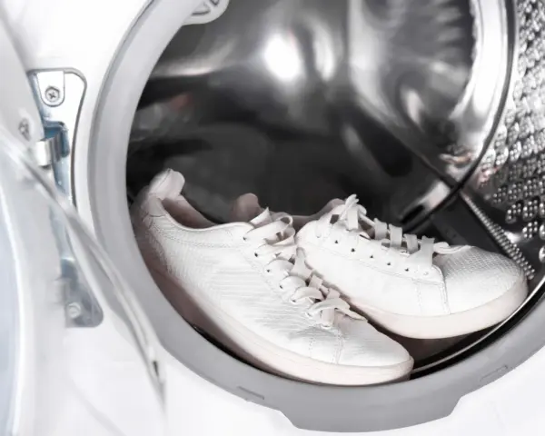 Weiße Sneaker warten in der Waschmaschine auf ihre Reinigung.