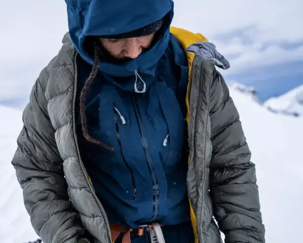 Person in Daunenjacke in winterlicher Berglandschaft. Die Daunenjacke waschen ist wichtig für die Langlebigkeit.
