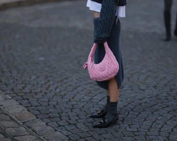 Ein grauer Strickrock kombiniert mit einem Oversize-Pullover und einer pinken Tasche.
