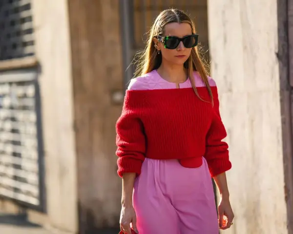 Frau in rotem Off-Shoulder-Pullover und rosa Hose. Eine tolle Farbkombination, die zeigt, welche Farbe passt zu roter Kleidung: Rosa!