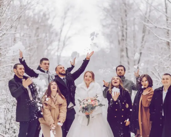 Fröhliche Gäste werfen Schnee in der Luft. Das Brautpaar strahlt, während die Gäste ihr silberhochzeit outfit tragen.