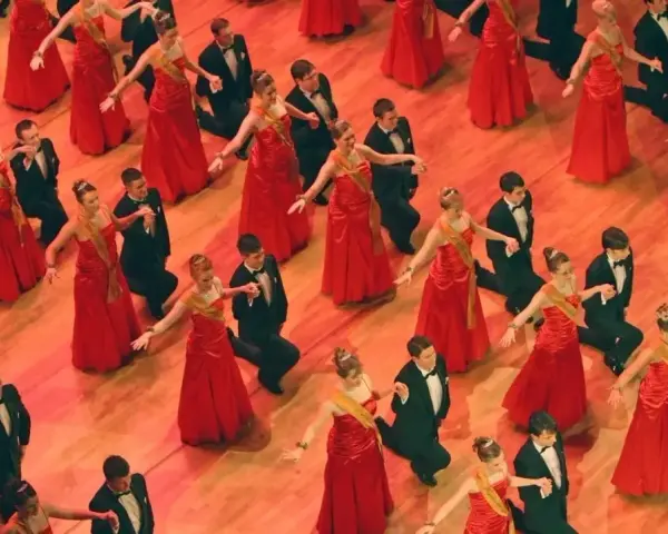 Junge Paare in roten Kleidern und schwarzen Anzügen tanzen. Die Kleiderordnung der Semperoper wird hier elegant umgesetzt.