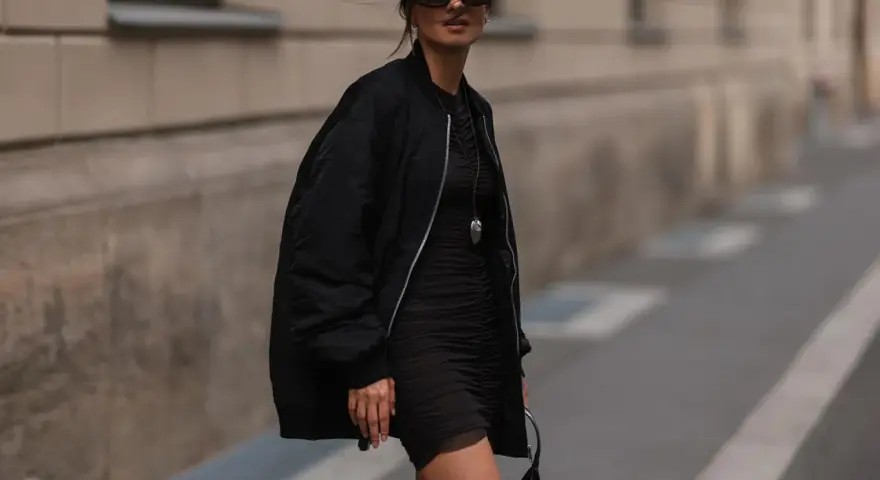 Stylische Frau in schwarzer Bomberjacke und engem Kleid. So kann man eine Bomberjacke kombinieren, Damen!