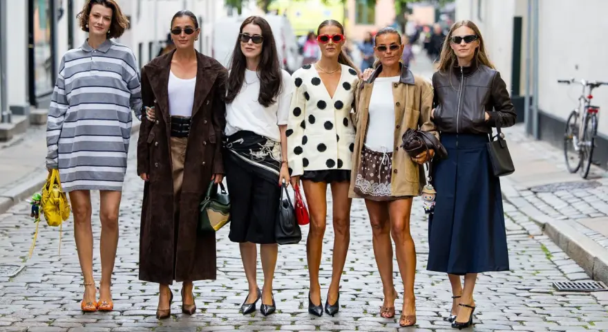 Sechs Frauen präsentieren ihren **scandi look** auf Kopfsteinpflaster. Von gestreiften Kleidern bis zu Lederjacken – ein vielfältiger Stilmix.