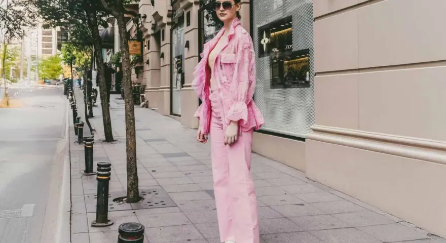 Eine Frau in einem auffälligen Outfit mit pinker Hose und passender Jacke. Ein modisches Statement, wie man pinke Hose kombinieren kann.
