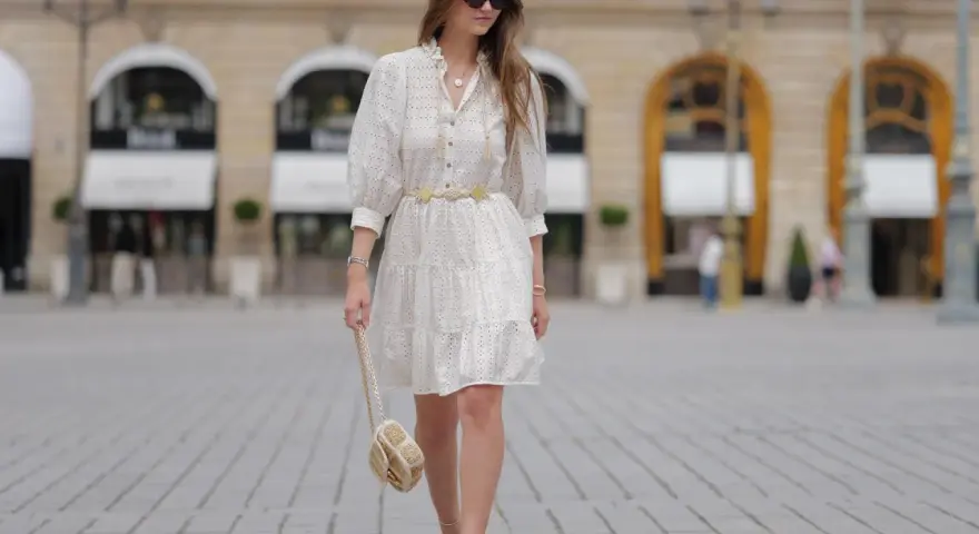 Sommerliches Outfit für eine Gartenparty: Weißes Lochstick-Kleid, goldener Gürtel, Sandalen und eine kleine Umhängetasche.