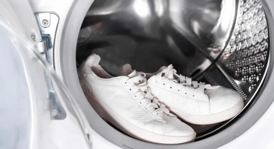 Weiße Sneaker warten in der Waschmaschine auf ihre Reinigung.