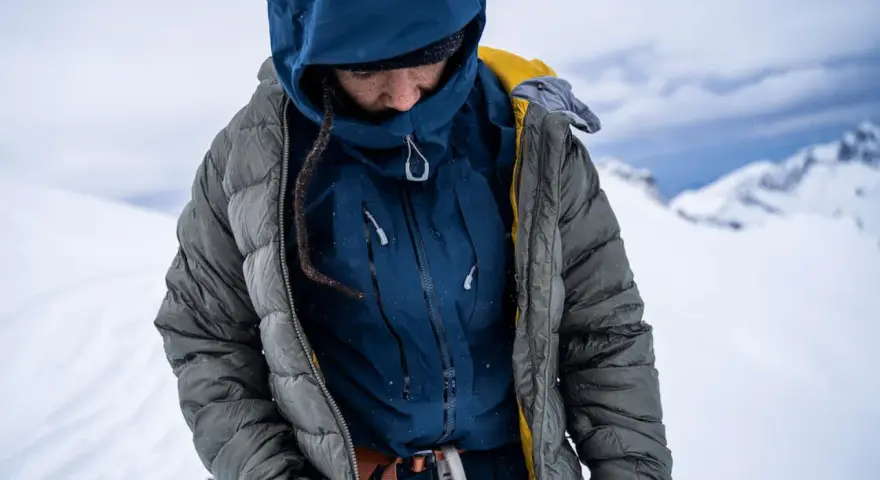 Person in Daunenjacke in winterlicher Berglandschaft. Die Daunenjacke waschen ist wichtig für die Langlebigkeit.