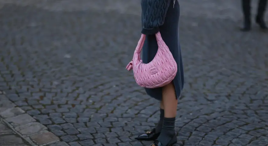 Ein grauer Strickrock kombiniert mit einem Oversize-Pullover und einer pinken Tasche.