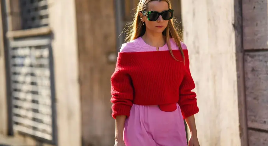 Frau in rotem Off-Shoulder-Pullover und rosa Hose. Eine tolle Farbkombination, die zeigt, welche Farbe passt zu roter Kleidung: Rosa!