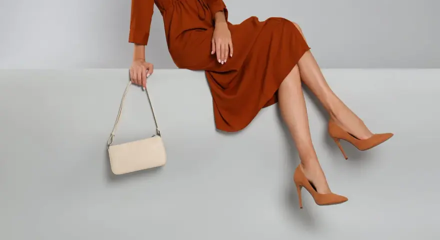 Elegantes Outfit für die Oper: Ein rostbraunes Kleid, cremefarbene Tasche und braune Pumps. So zieht man in die Oper an.