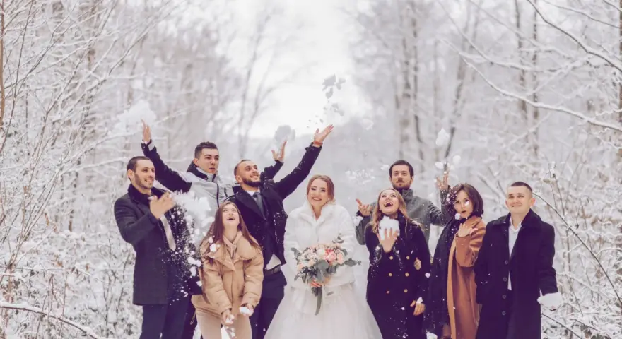 Fröhliche Gäste werfen Schnee in der Luft. Das Brautpaar strahlt, während die Gäste ihr silberhochzeit outfit tragen.