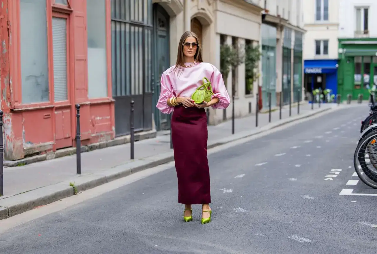 Frau in pinker Bluse und bordeauxrotem Rock, welche Farbe passt zu schwarz? Sie tr&auml;gt neongr&uuml;ne Schuhe und Tasche.