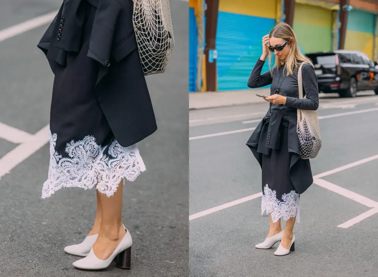 Eine Frau kombiniert einen Spitzenrock mit einem Oversized-Blazer und weißen Pumps.