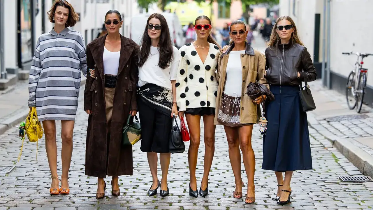 Sechs Frauen präsentieren ihren scandi look auf Kopfsteinpflaster. Von gestreiften Kleidern bis zu Lederjacken – ein vielfältiger Stilmix.