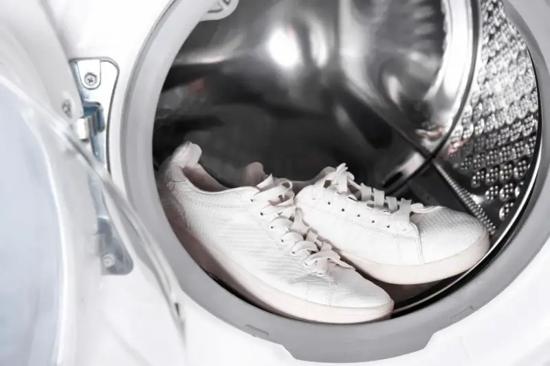 Weiße Sneaker warten in der Waschmaschine auf ihre Reinigung.