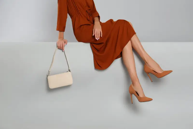 Elegantes Outfit für die Oper: Ein rostbraunes Kleid, cremefarbene Tasche und braune Pumps. So zieht man in die Oper an.